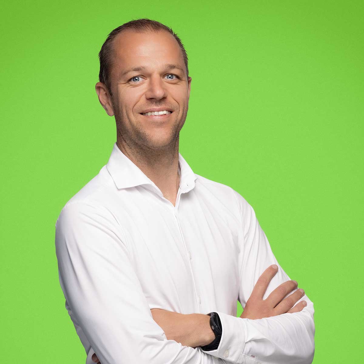 The image shows a person wearing a white shirt with their arms crossed. The background is a solid green color.