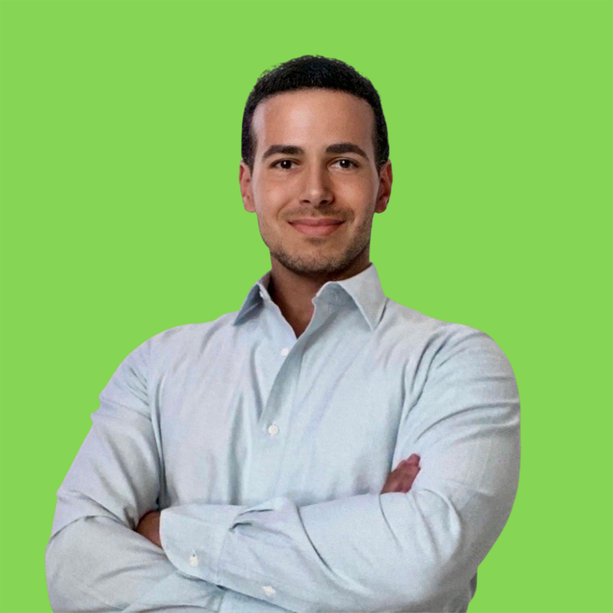 A person wearing a light blue shirt with arms crossed. The background is a solid green color.