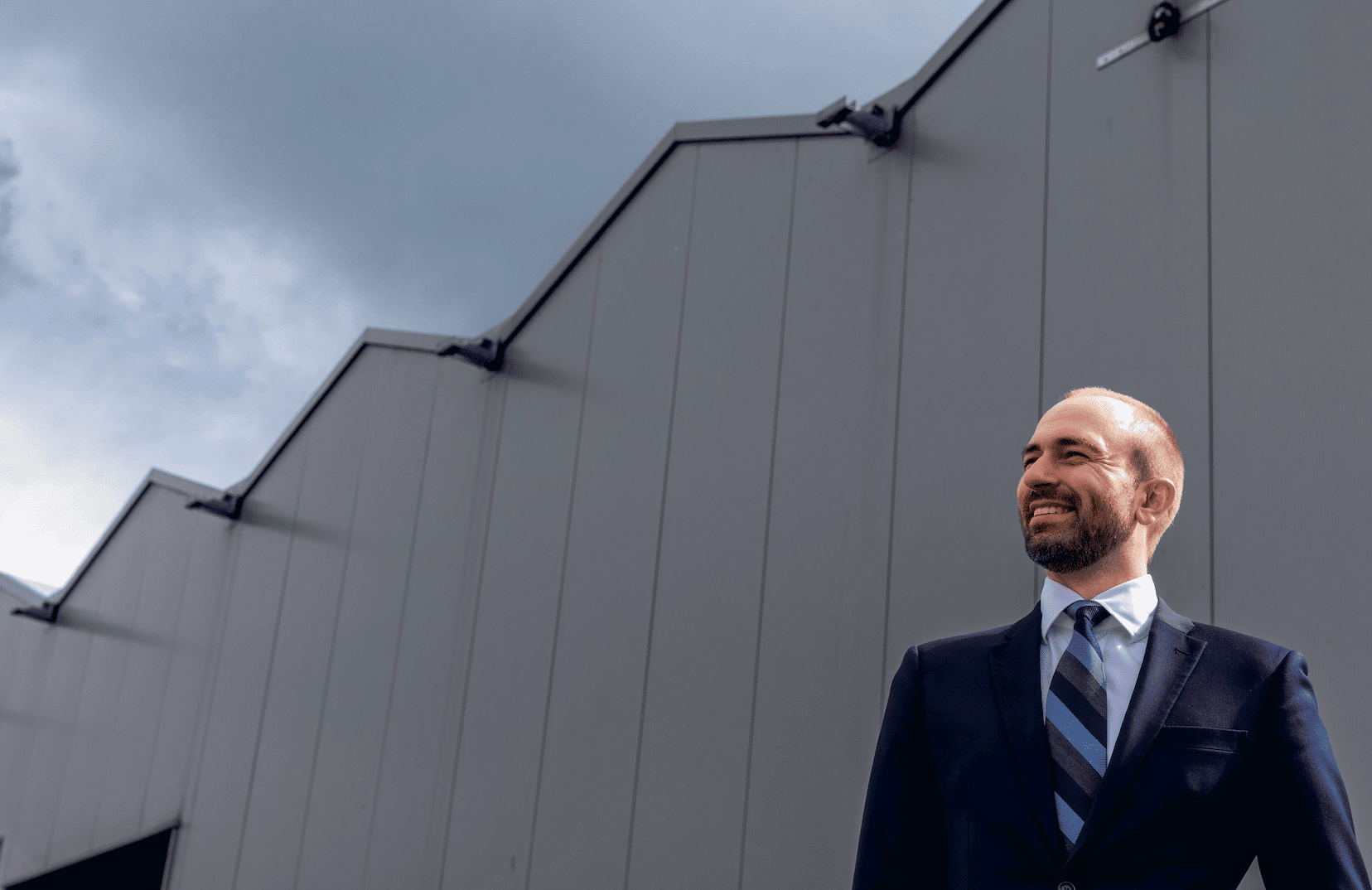 Men behind a greenhouse in a suit and a tie.