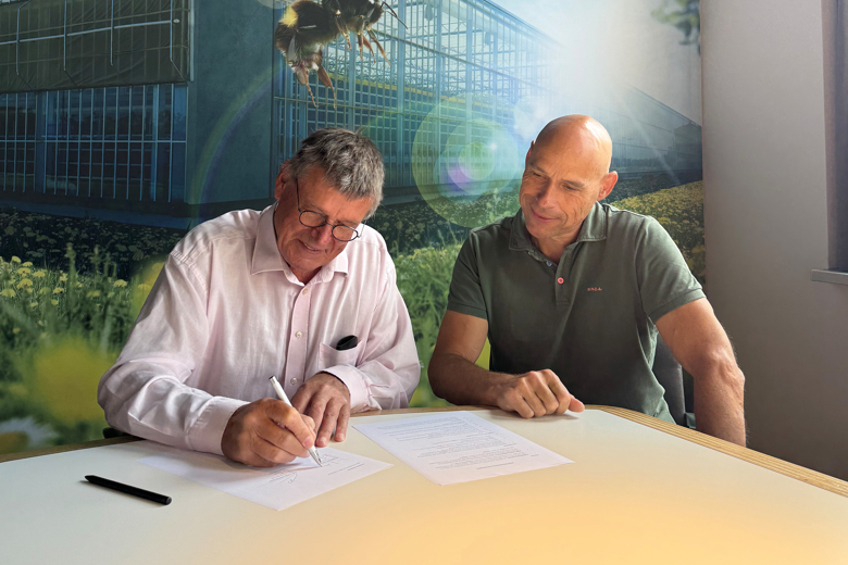 Two men signing an agreement at a table
