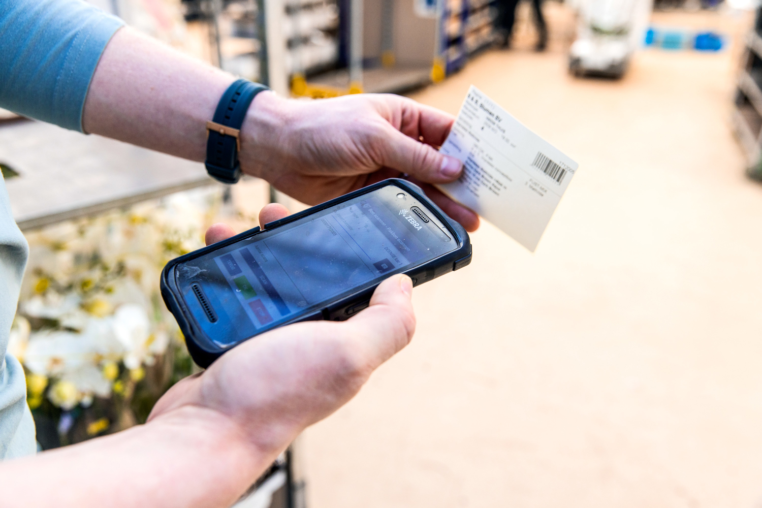 Two men's hands scan a packing slip with a terminal